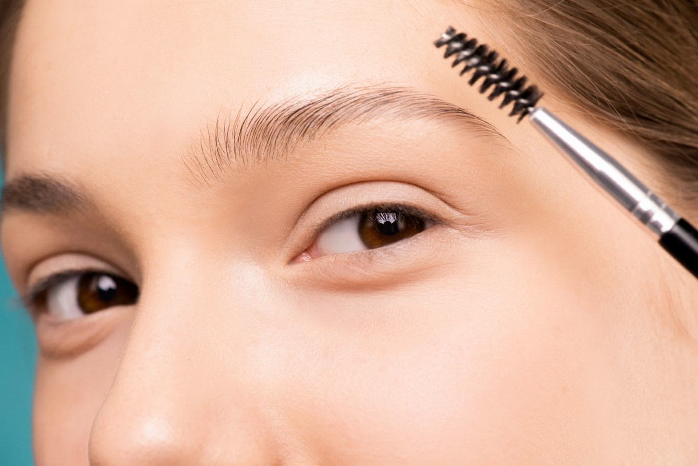 Brushing fluffy, laminated eyebrows upward with a spoolie