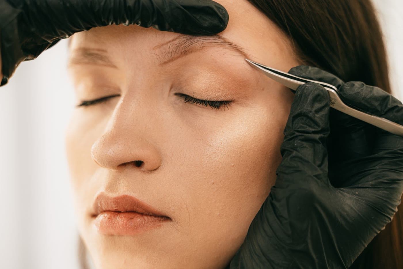 An eyebrow being shaped with tweezers during a grooming appointment
