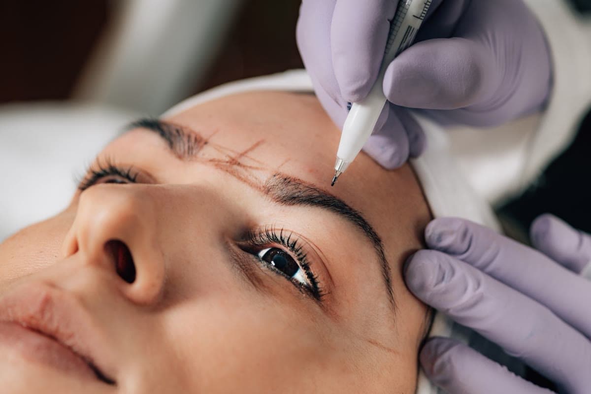 Close-up of a permanent makeup brow tattoo procedure being mapped and applied