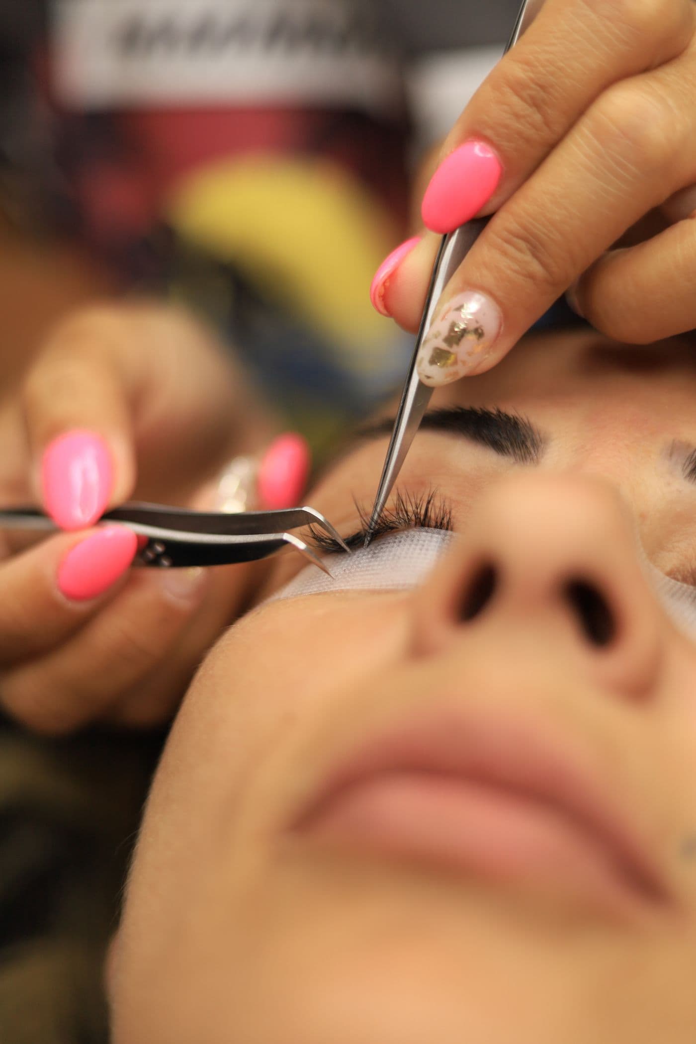 A lash artist isolating a single natural lash with tweezers during an eyelash extension appointment