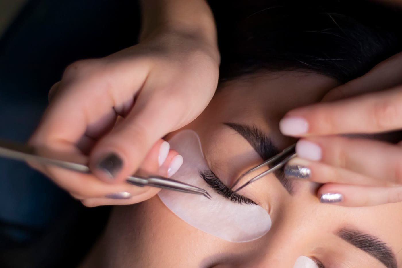 A lash artist applying an eyelash treatment to a relaxed client